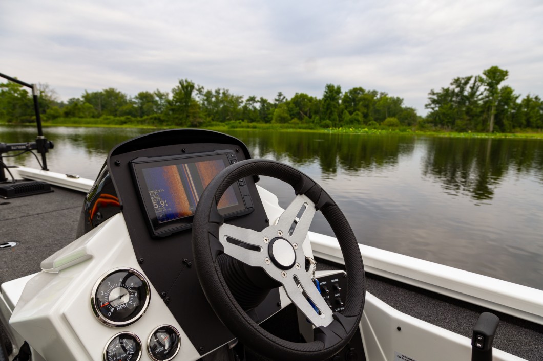 A modern sports fishing boat sitting out on the water with electronics equipment and dashboard display.